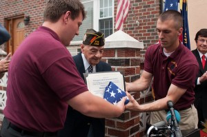 Previous VFW Post 2348 Commander, Mike Mehltretter, and Previous Quartermaster Timothy Irish, carefully handling the American flag and certificate for Rocco Moretto.
