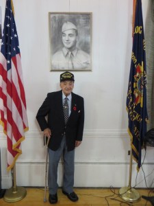 Rocco standing under the portrait that was presented to him on the 70th Anniversary of D-Day.